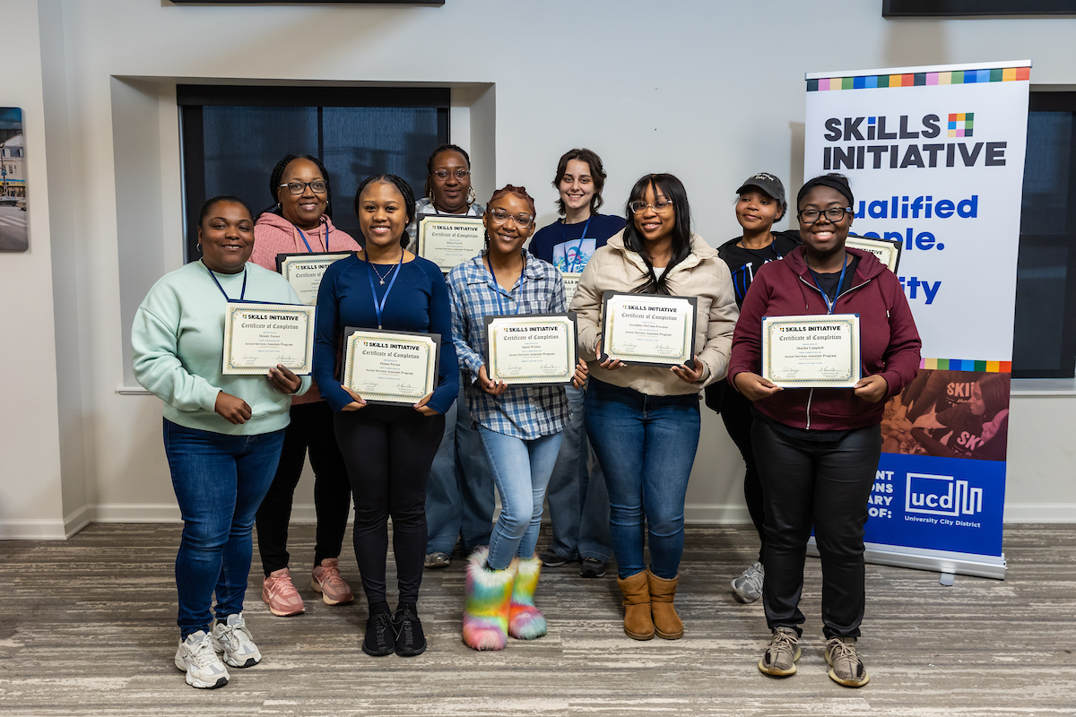 Smiling graduates form the Skills Initiative pose with their graduation certificates.