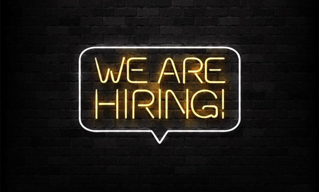 A neon sign saying "We Are Hiring"