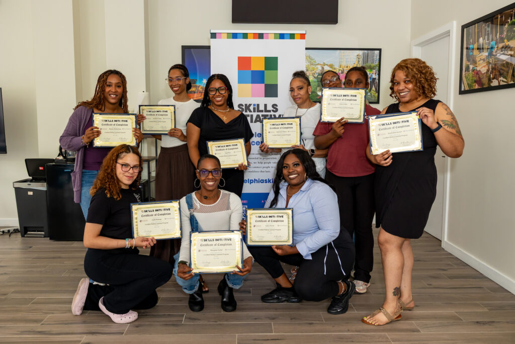 A group of Skills Initiative participants posing with the degrees.